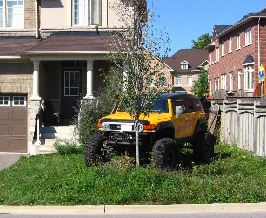 желтый внедорожник припаркован на газоне.